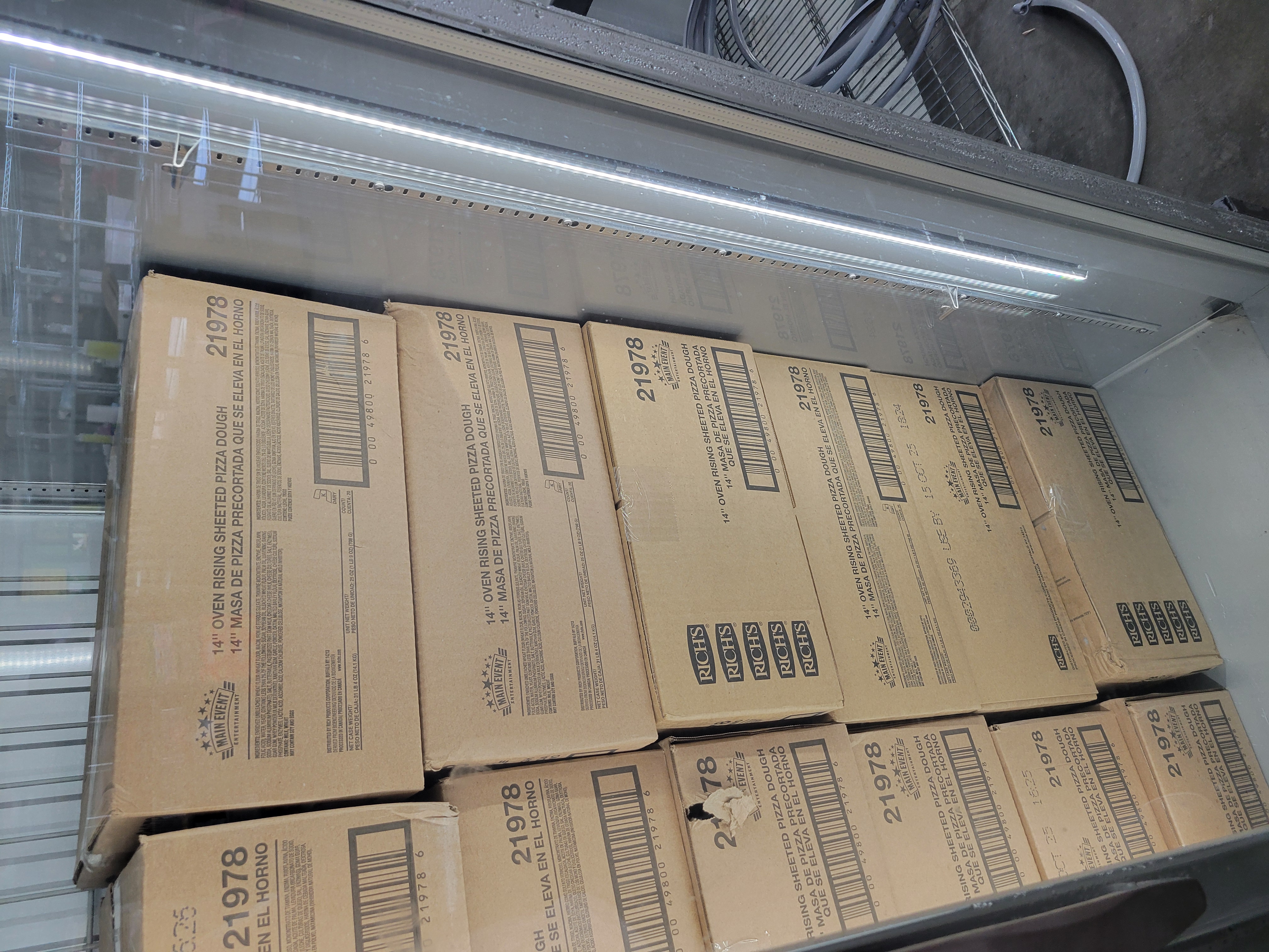 Long cardboard boxes of oven rising sheeted pizza dough.